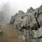 A misty mountain trail winds through jagged rocks, creating a mysterious and serene atmosphere.