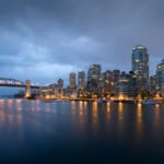 Daft Punk City skyline at dusk with a bridge and lights reflecting on water.