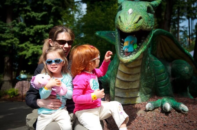 A family enjoys a sunny day visiting a dragon statue at an outdoor attraction.