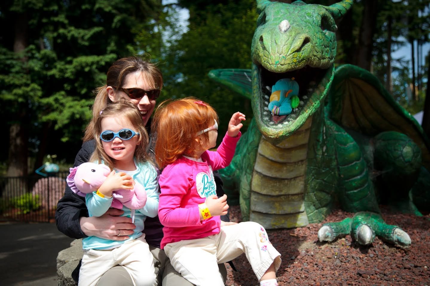 Enchanted Village & Wild Waves A family enjoys a sunny day visiting a dragon statue at an outdoor attraction.
