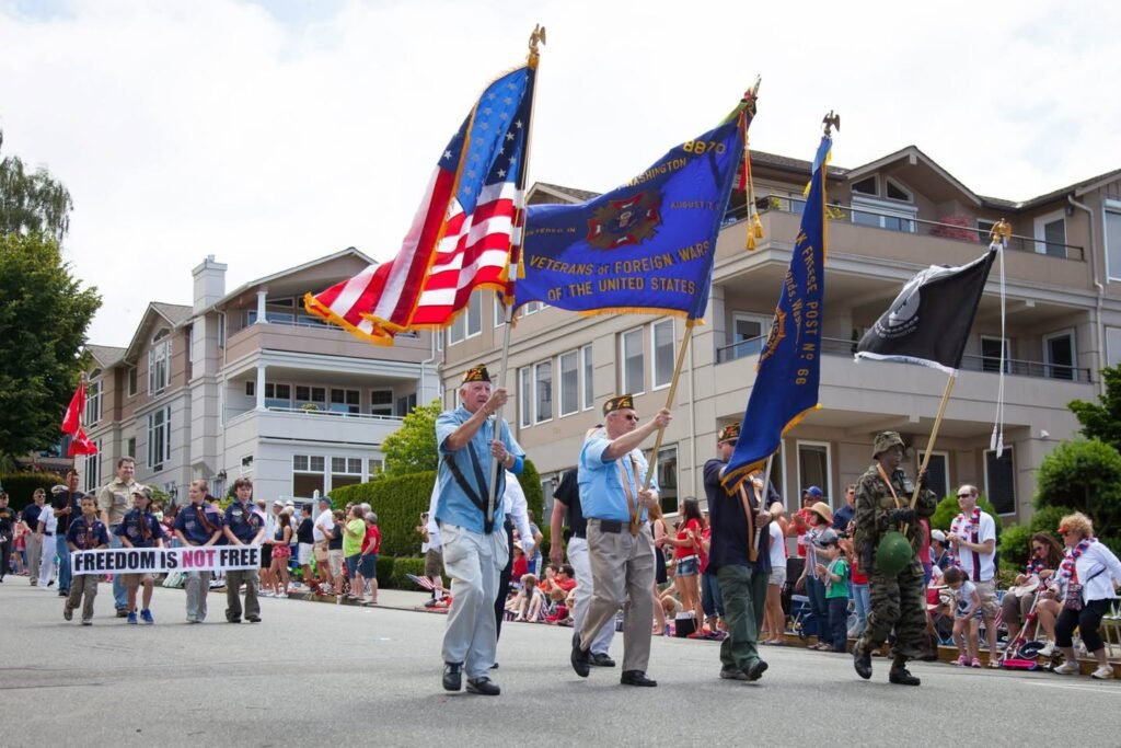 A color guard carries Oregon, American, and other state flags during a parade, with a marching group visible behind them.