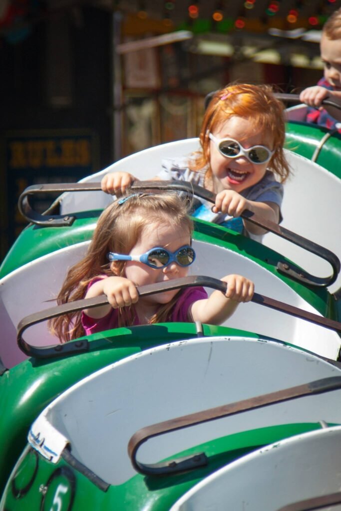 A collage of photos showing children wearing sunglasses and riding on a green amusement park ride.