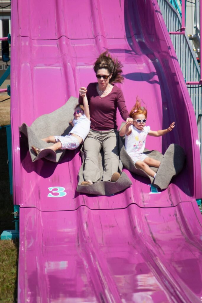 A family slides down a bright pink water chute at an amusement park, enjoying the thrill of the ride together.