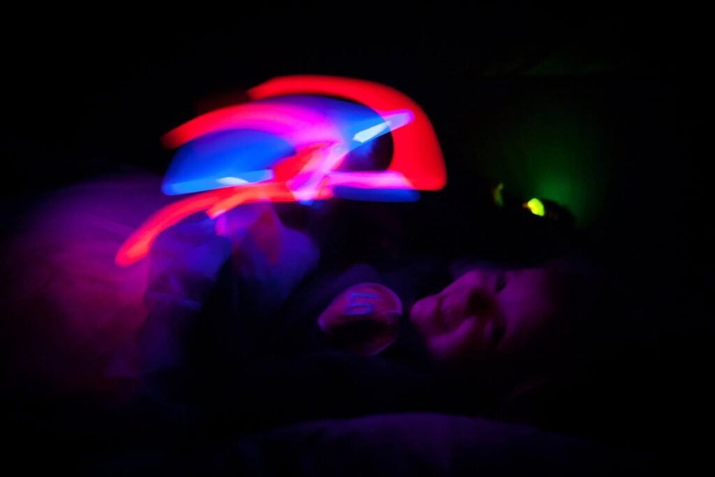 Vibrant neon light trails glow brightly red, blue and purple in a dark environment.