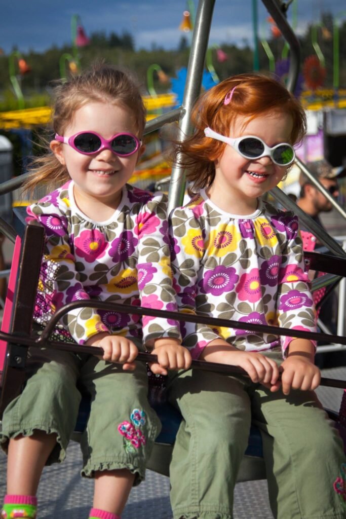 Children enjoying a ride at an outdoor state fair park on a sunny day.