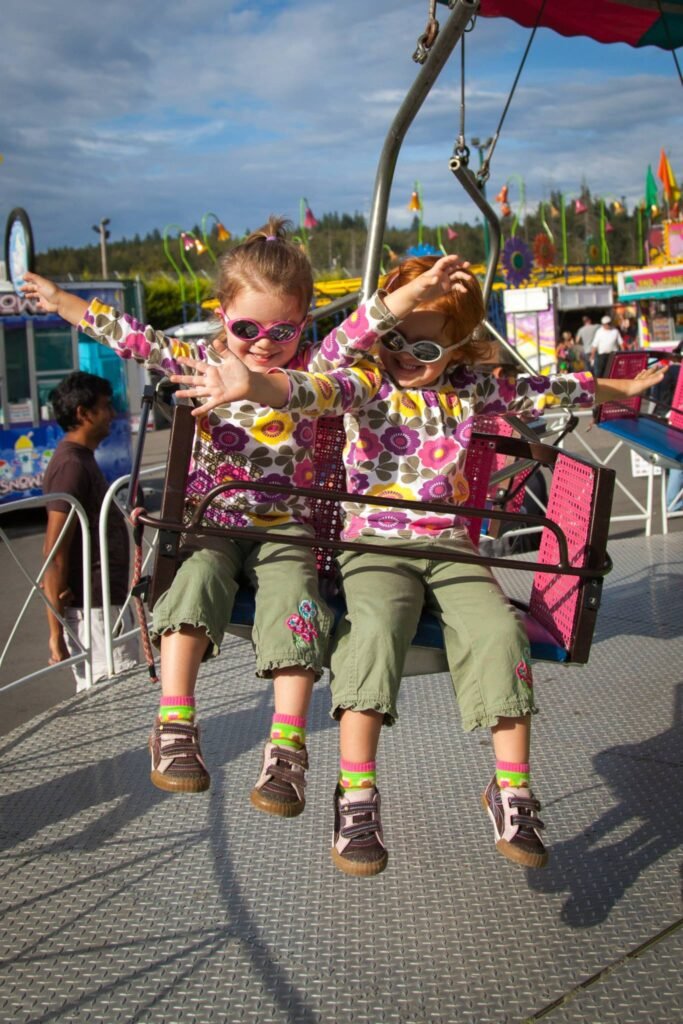 Two people enjoying a carnival ride on a sunny day abroad.