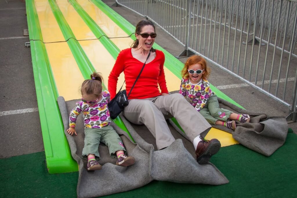 A family sliding together down a bright yellow and green luge track at an amusement park, capturing the thrill of a shared outdoor adventure.