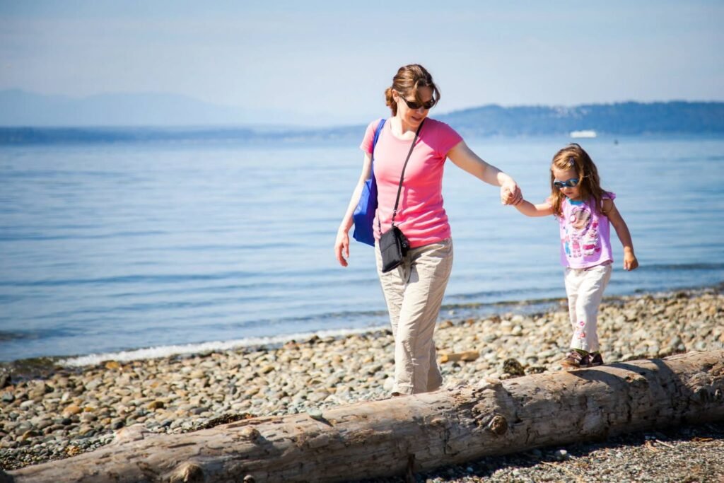 Walking hand-in-hand along a rocky beach, balancing on driftwood in the sun.