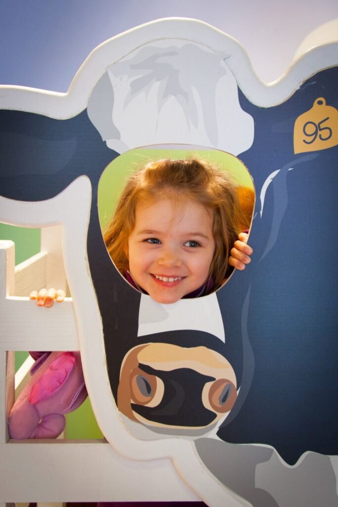 A child smiles warmly while peeking through a cutout in a whimsical sculpture at the 2010 Shanghai World Expo.