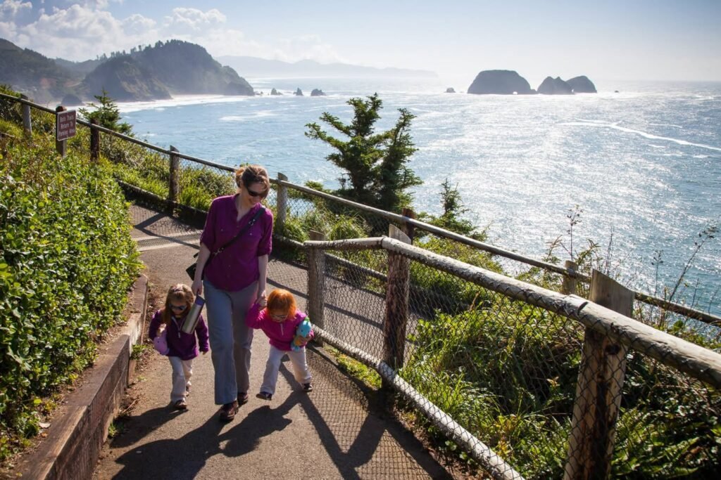 A family walking along a scenic coastal trail with a view of the ocean and distant islands.