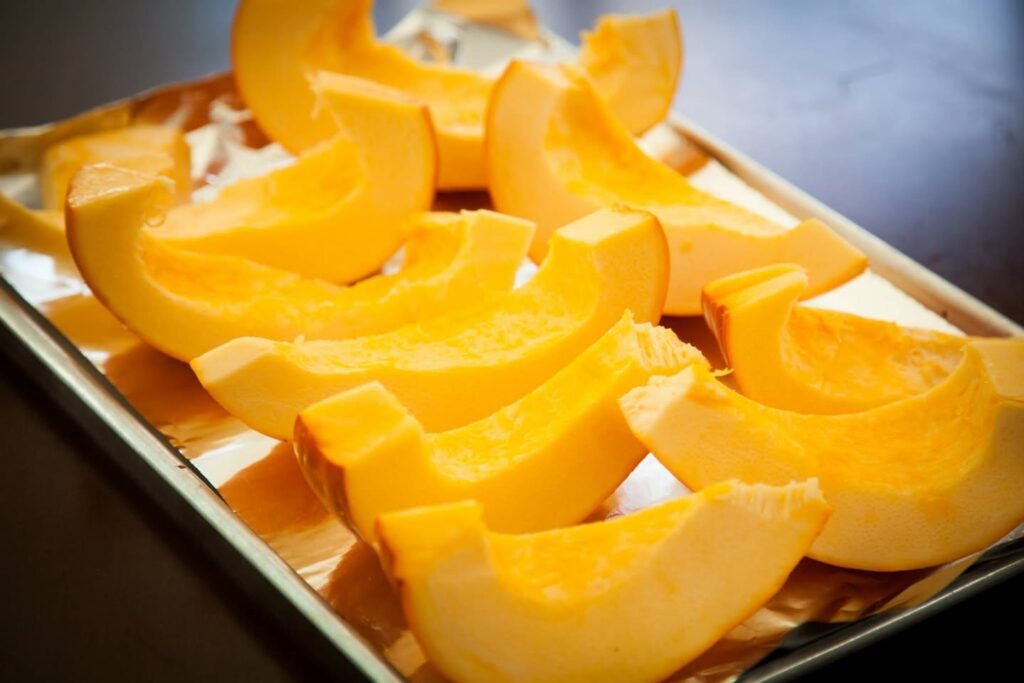 Golden butternut squash wedges arranged on a foil-lined baking sheet, ready to roast.