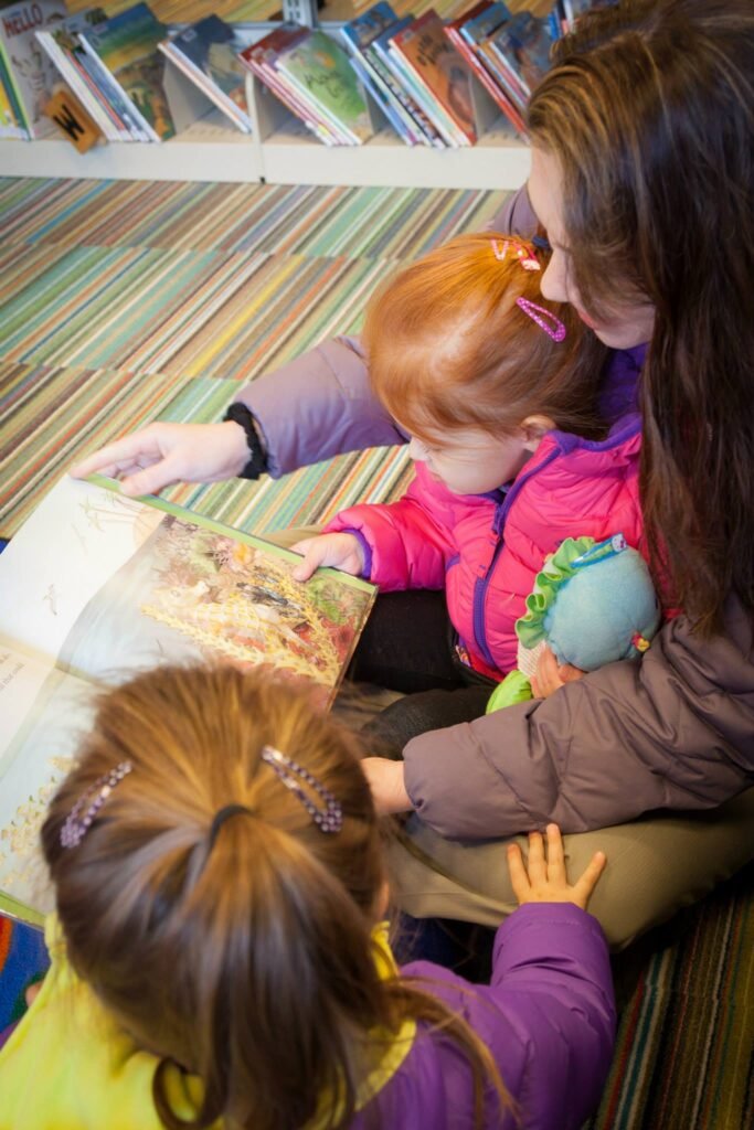A family sitting together on a striped carpet, sharing a children's picture book.
