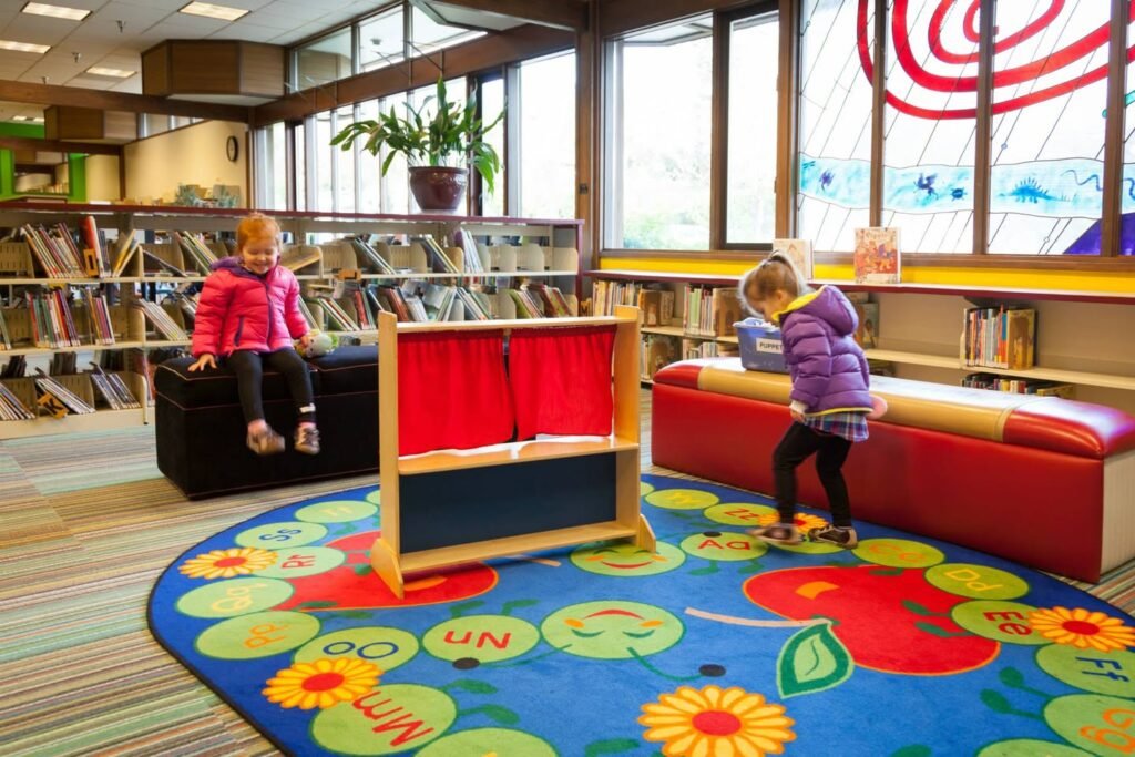 A colorful children's area in a library with playful rugs and bookshelves.