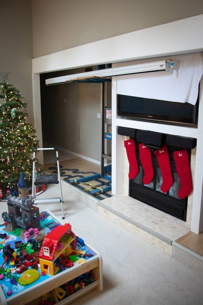 A cozy living room decorated for Christmas with red stockings hanging on a fireplace and a Lego table in the foreground.