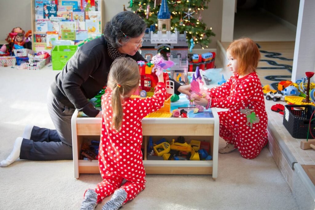 A family enjoys playing with toys and presents on Christmas morning. The children wear matching red pajamas with white polka dots.