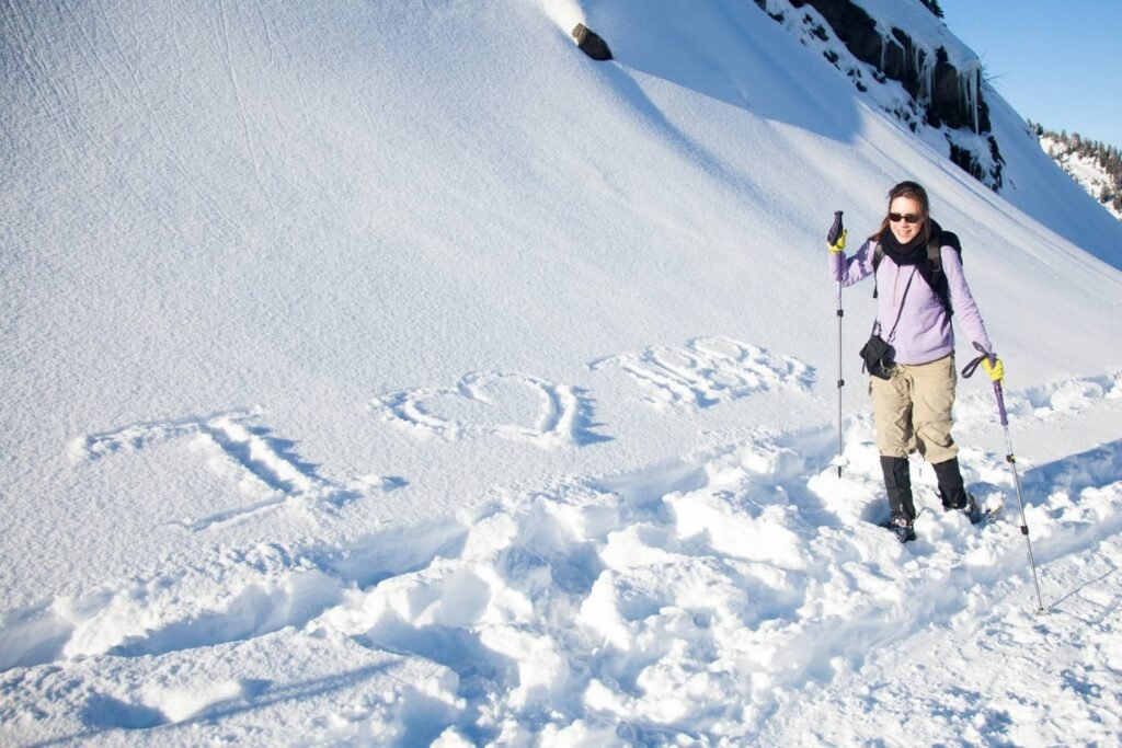 A person stands on a snowy slope with poles, next to large letters spelling out LOVE in the snow. A separate photo shows a black and white bird perched on a snowy branch.