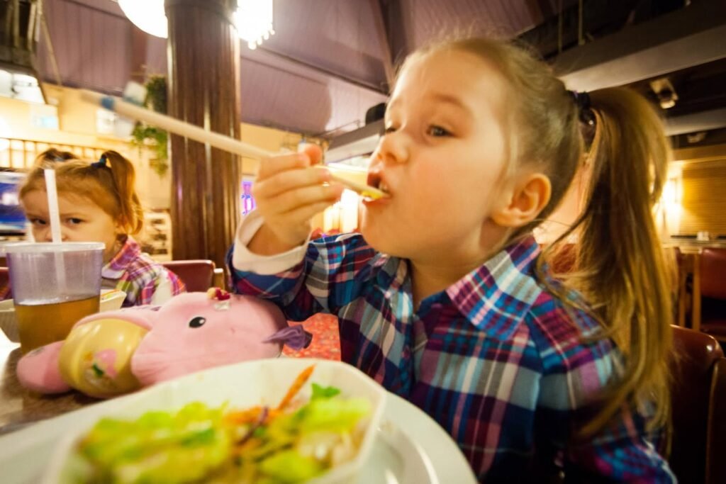 A child enjoys a meal at a family restaurant with a colorful plate in front of them.