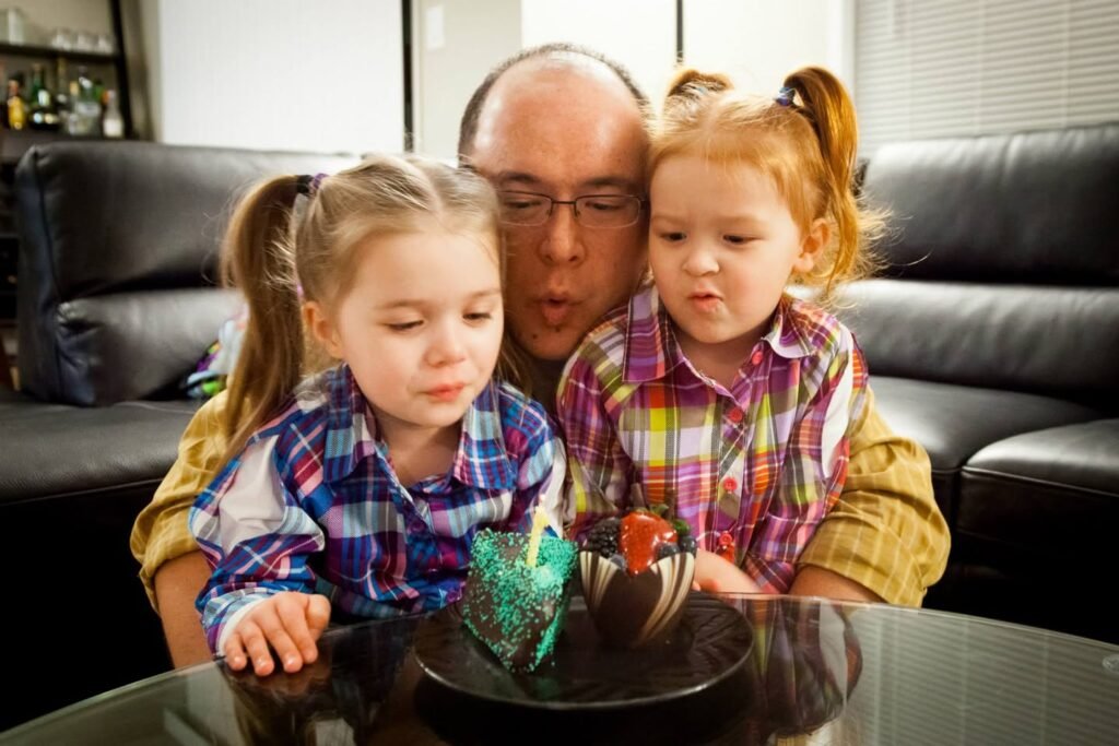 A family gathers around a table to blow out birthday candles together.