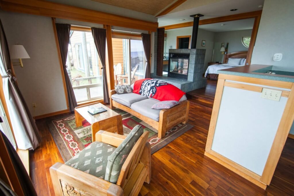 Spacious suite interior featuring a living room with wooden furniture, a wood stove, and an adjacent bedroom visible through an open doorway.