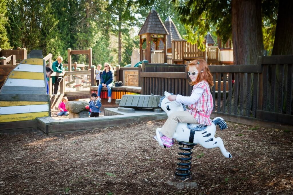 A child rides a spring-mounted playground horse while others play near a wooden structure.