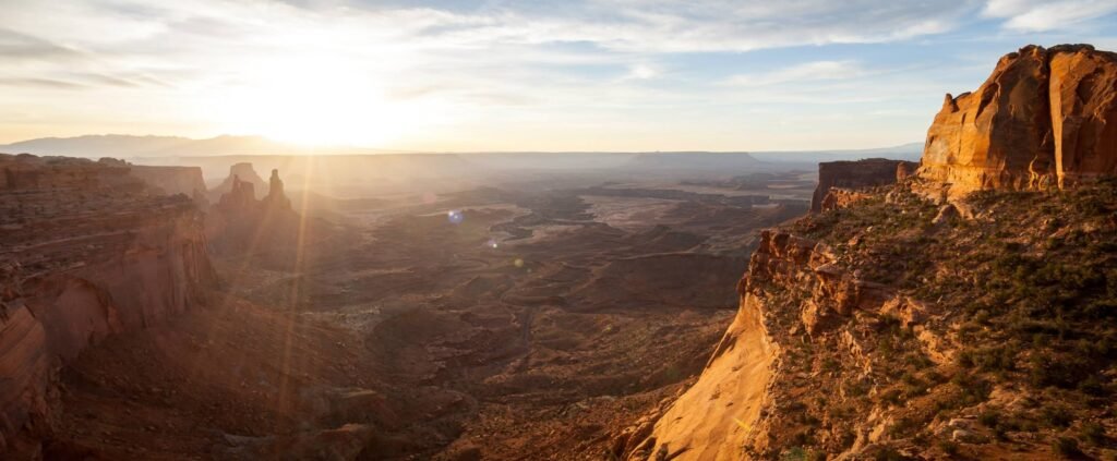 A panoramic view of a vast canyon at sunset, highlighting dramatic rock formations and the expansive landscape.