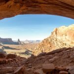 A scenic panoramic view of desert cliffs and rocky terrain seen through an open natural arch.