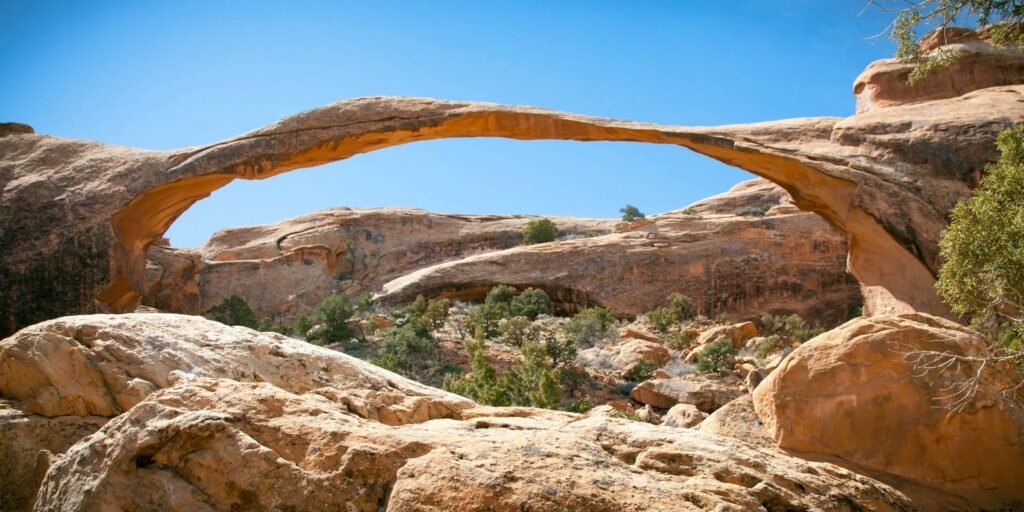 A close-up view of textured natural rock arches set against a clear blue sky.