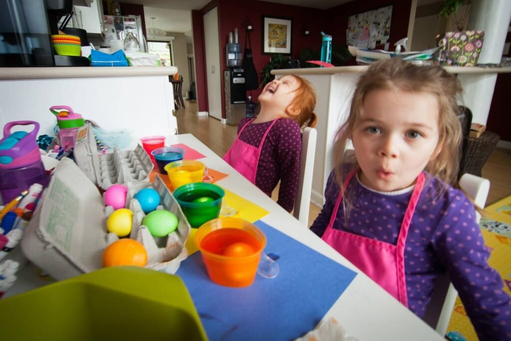 Children enjoying Easter egg painting at the kitchen table with colorful eggs and dyes.