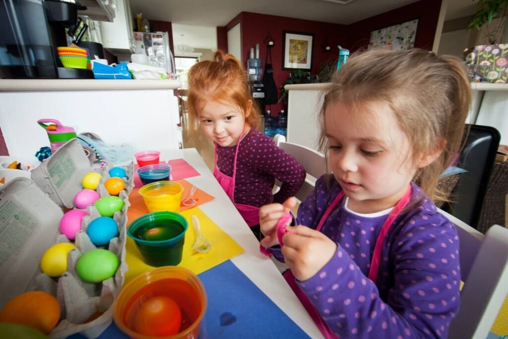 Children enjoy colorful Easter egg dyeing activities at a family table, with vibrant eggs and dye cups nearby.