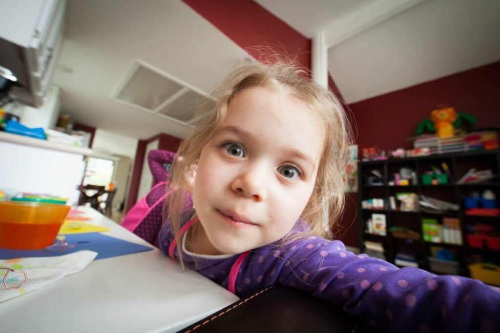 A child in a purple top playing at a table in a room with red walls.
