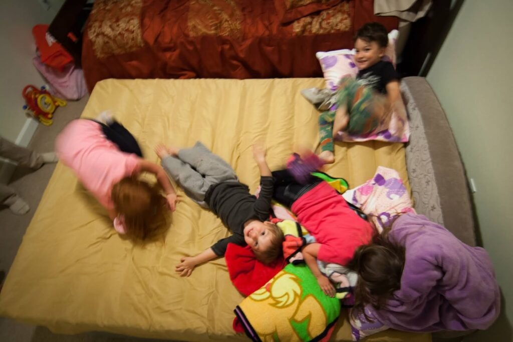 A group of children playing and sleeping on a yellow bed in a cozy bedroom.