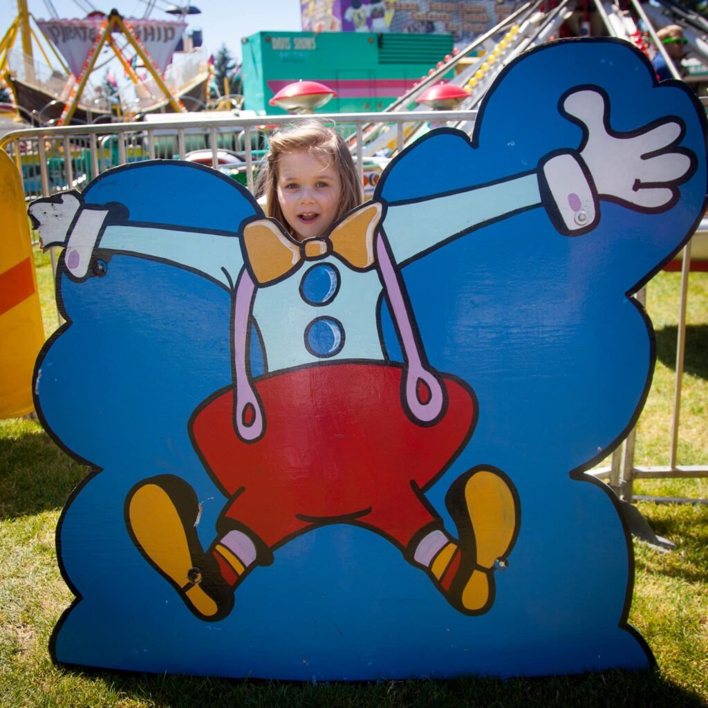 A child smiles while peeking through a cutout of the Blue Humper fairy tale character.