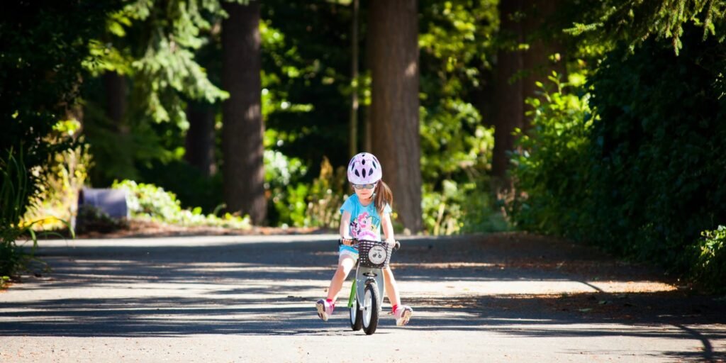 Child on bicycle on quiet street near trees