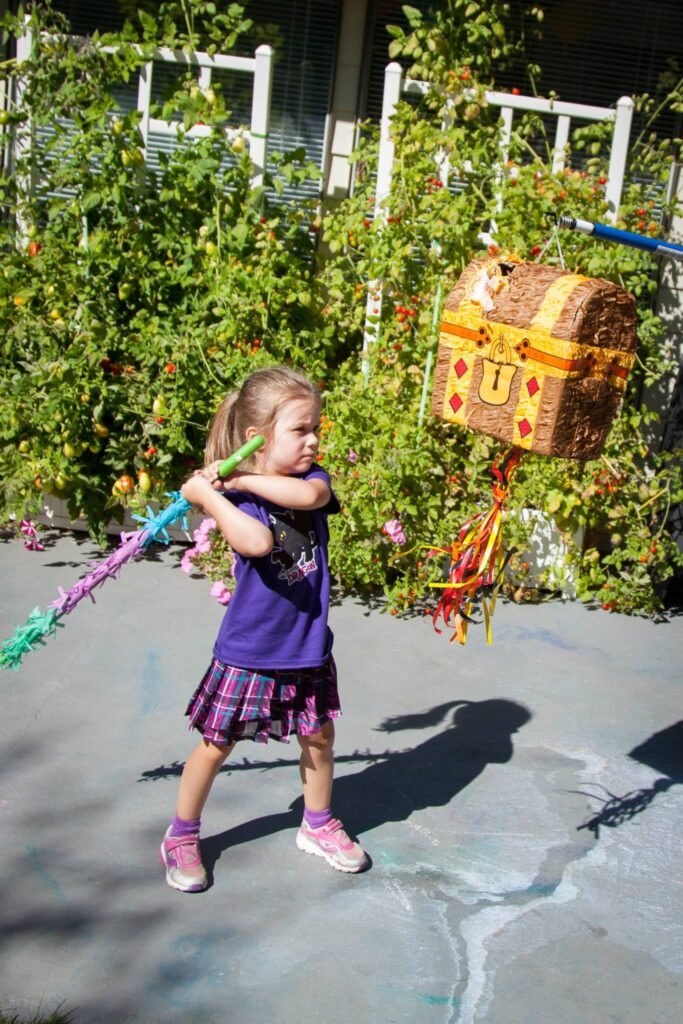 A joyful child swings a colorful stick at a pinata.