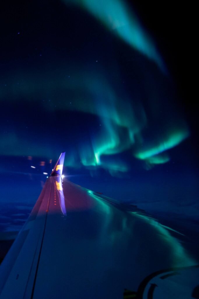The stunning aurora borealis dances across a dark night sky above a road at night.