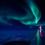 Vibrant aurora borealis glowing in the night sky above the Pacific Ocean.