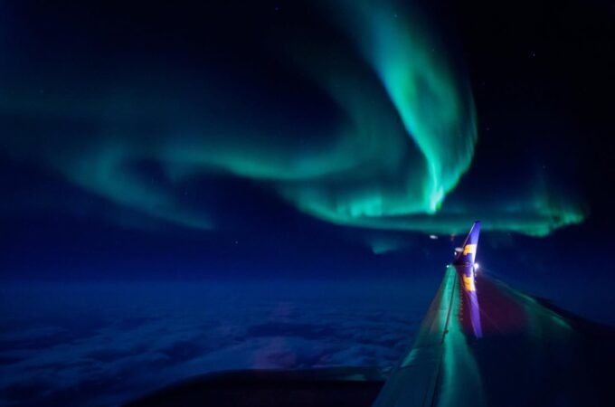 Vibrant aurora borealis glowing in the night sky above the Pacific Ocean.
