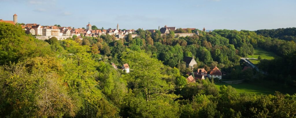 A panoramic view of a European village nestled among rolling green hills.