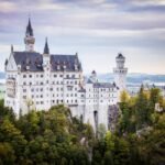 Munich A scenic photo blog post featuring the iconic Neuschwanstein Castle in Germany, showcasing its turrets and surrounding Alpine landscape.