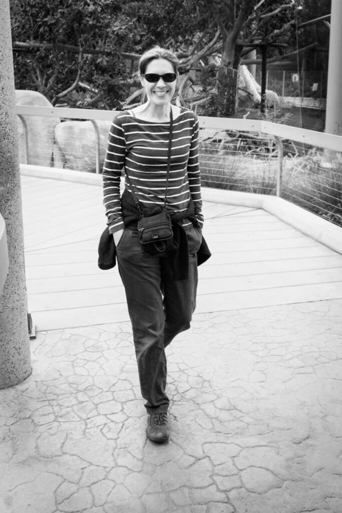 A traveler walks through a modern sculpture garden. The setting features architectural elements and seating areas.