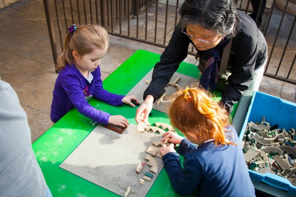 Children are focused on arranging wooden pieces on a green mat.