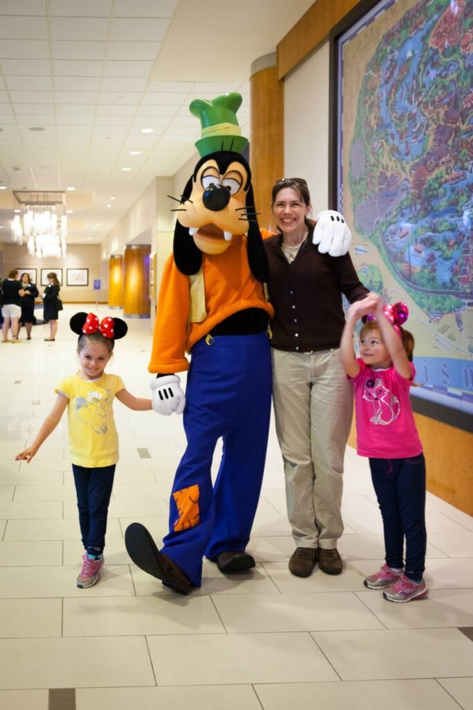 A family posing with the costumed character Goofy in a Disney resort hallway.