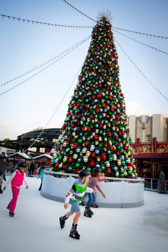 Ice skaters glide past a large decorated Christmas tree with glowing ornaments under holiday string lights at Northglenn Mall in Colorado.