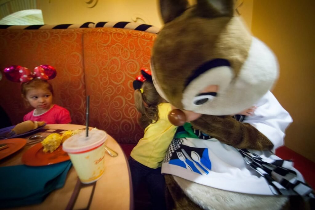 Children in a restaurant booth with plush characters in warm lighting.