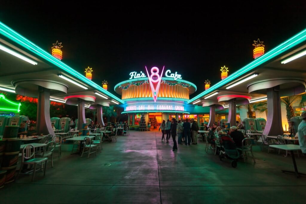 A neon-lit outdoor cafe at night with people dining under colorful lights.