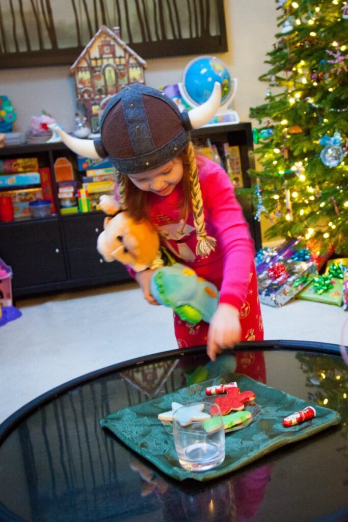A child wearing a reindeer hat and red outfit engages in crafts at a table shaped like the Amazon River, with a Christmas tree in the background.