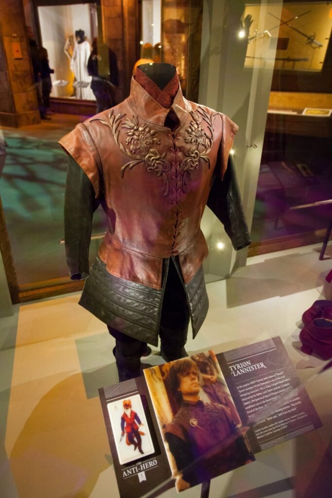 A detailed embroidered jacket on a mannequin is displayed with informational placards in a museum exhibit.