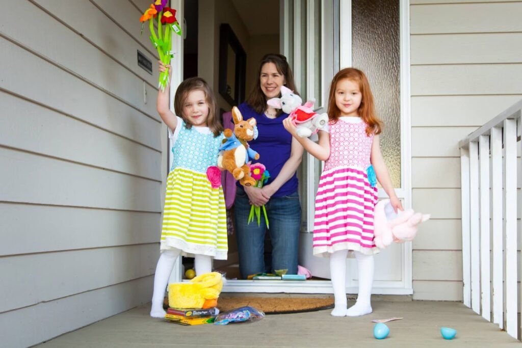 A family stands on their front porch holding colorful Easter eggs and plush toys. Bright colors contrast against the neutral siding of the house.