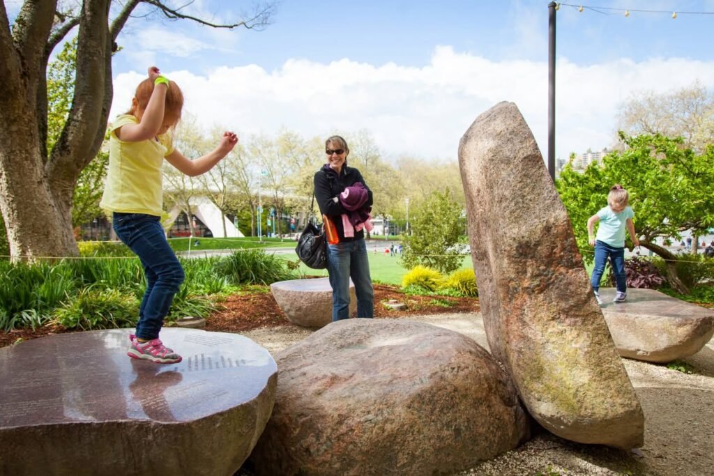 People play around large stone sculptures in a park.