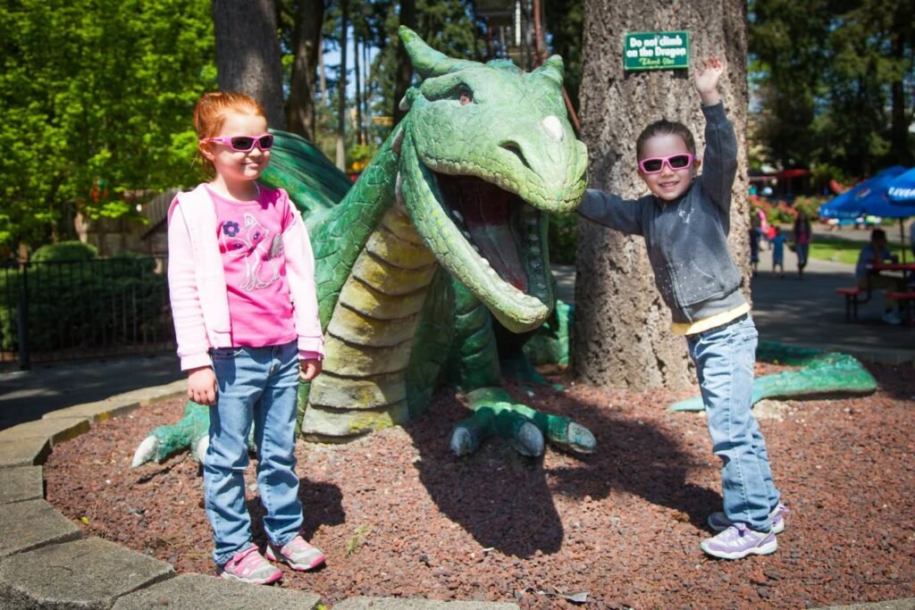 Two children pose playfully beside a large dragon sculpture in a park. A close-up highlights the intricate details of the dragon's head.